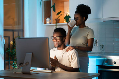 Happy african couple work on startup project at home office late, build family-owned online business