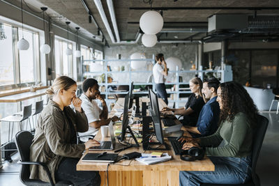 Happy male and female programmers coding while sitting in tech startup office