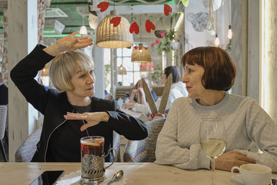 Two seniors women talking in cozy cafe