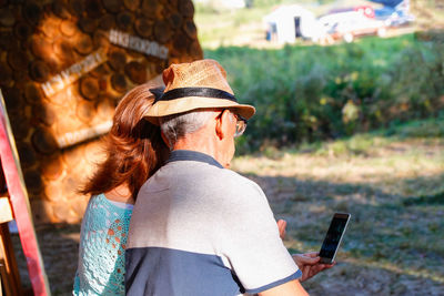 Side view of senior man and woman using mobile phone