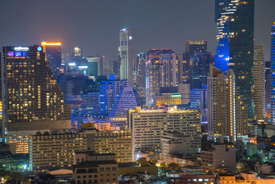 Illuminated buildings in city against sky at night