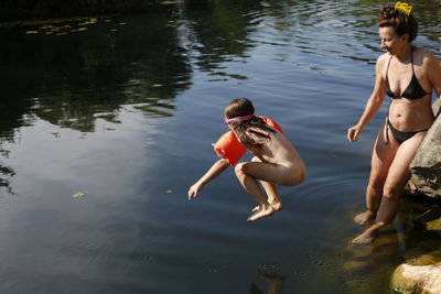 Little gir jumping off rocks into a lake