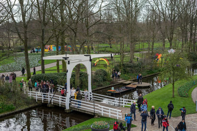 People on bridge over canal against trees