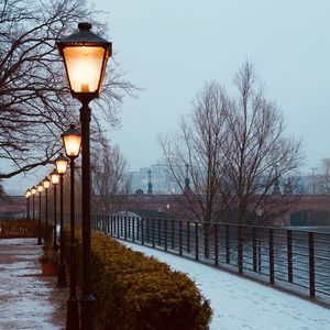 Street light and bare trees against sky during winter