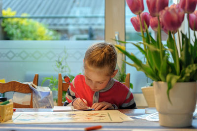 Portrait of boy holding flower vase on table