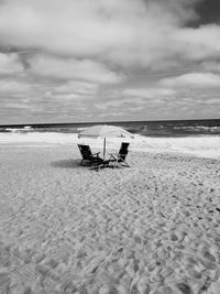 Chair on beach against sky