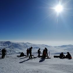 People on snowcapped mountain against sky during winter