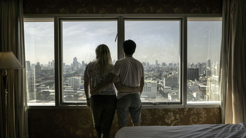 Rear view of couple looking through window