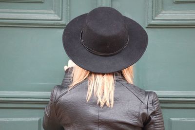 Rear view of woman wearing hat against closed door