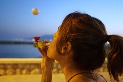 Close-up portrait of young woman drinking against sky