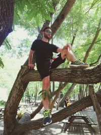 Full length portrait of man climbing tree trunk in forest