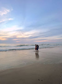 Couple on beach by sea against sky