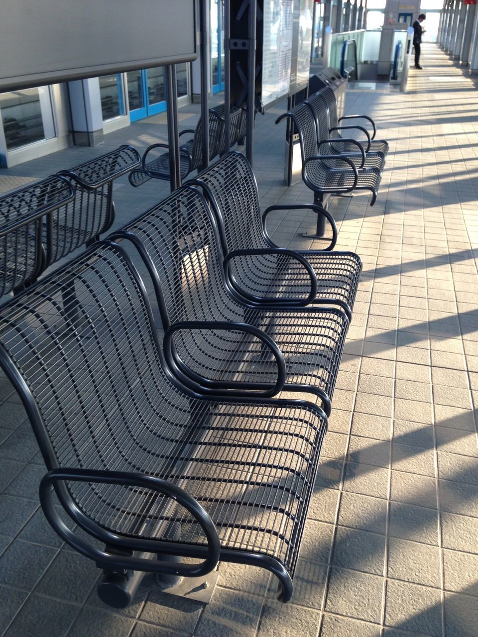 chair, empty, absence, seat, table, architecture, built structure, sunlight, sidewalk cafe, shadow, furniture, building exterior, tiled floor, restaurant, indoors, day, cobblestone, in a row, no people, relaxation