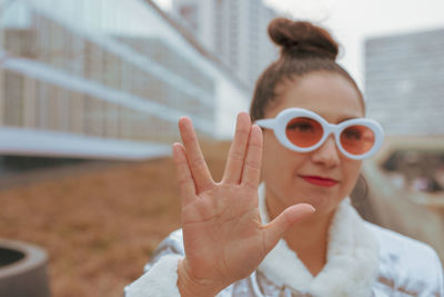 Woman in sunglasses gesturing against building