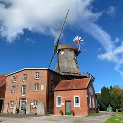 Low angle view of traditional windmill by building against sky