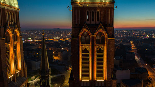 Illuminated buildings in city against sky during sunset