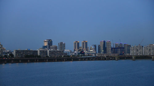 Sea by buildings against clear sky