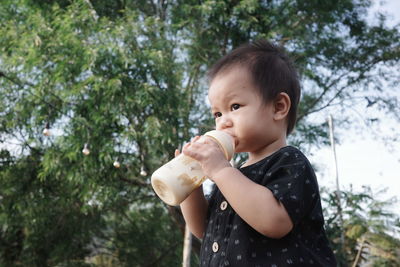 A baby is holding a bottle with both hands