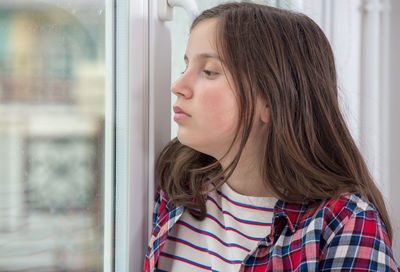 Portrait of teenage girl looking through window
