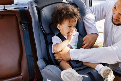 Man with toddler son sitting on seat in car