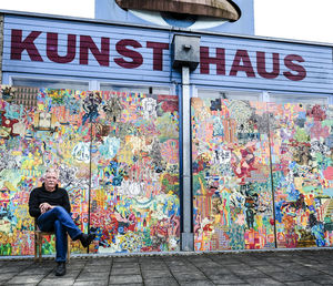 Germany, burghausen, painter sitting in front of his work at art house