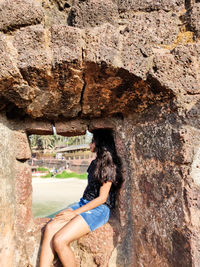 Side view of woman on rock against wall