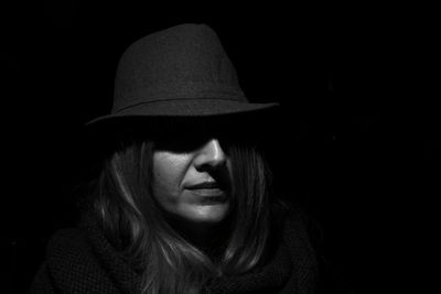 Close-up portrait of woman against black background