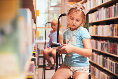 Schoolgirls looking for books in school library. elementary education. back to school