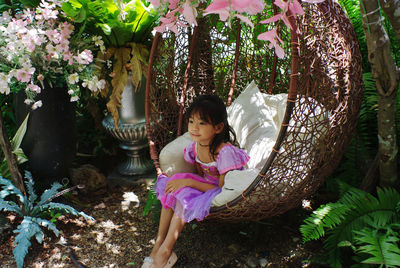 Full length of woman sitting on tree trunk