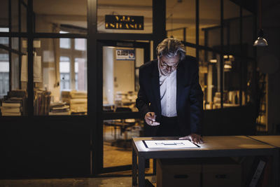 Senior businessman looking at shining tablet in office