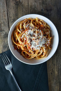 Linguine with tomato sauce and grated cheese on wooden table