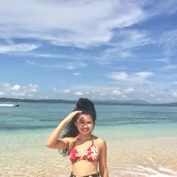 Portrait of smiling young woman standing on beach