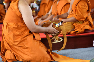 Hand of ordained buddhist man holding monk bowl and yellow bag.