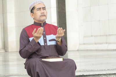 Mid adult man wearing hat sitting against wall