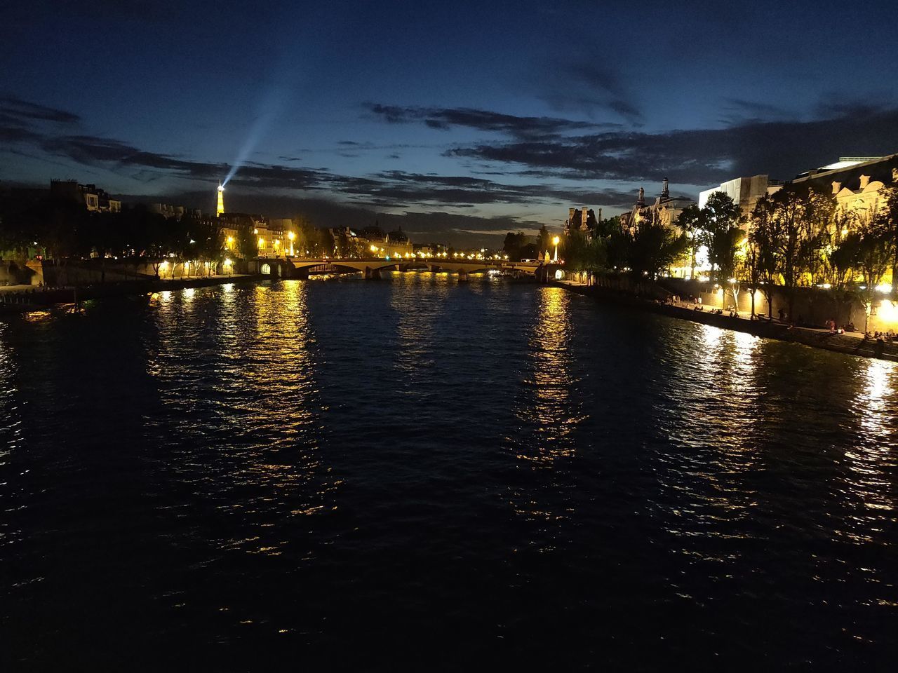 ILLUMINATED BUILDINGS BY RIVER AT NIGHT