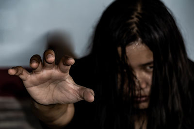 Close-up portrait of serious young woman showing stop gesture at home