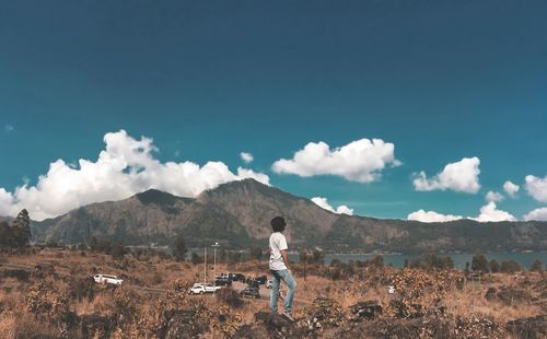 Rear view of man standing on rock against sky