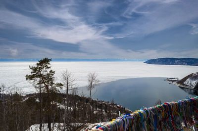 Scenic view of sea by snowcapped mountains against sky