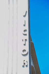 Low angle view of text on building against clear blue sky