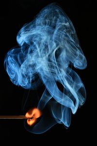 Close-up of burning matchstick against black background