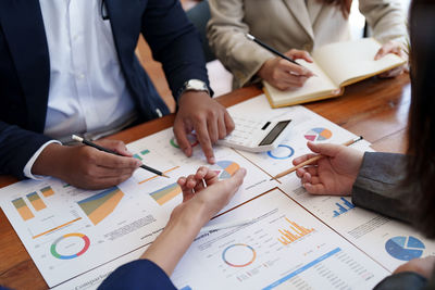 Midsection of business people working on table