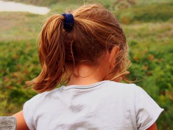 Rear view of girl with ponytail against plants