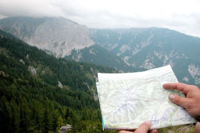 Midsection of person holding mountain against sky