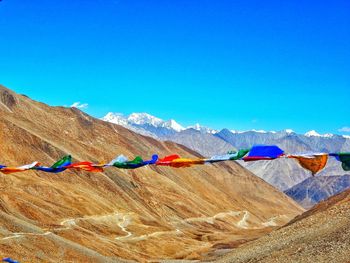 Colorful flags on mountain against clear blue sky