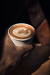 Cropped hand holding coffee on table
