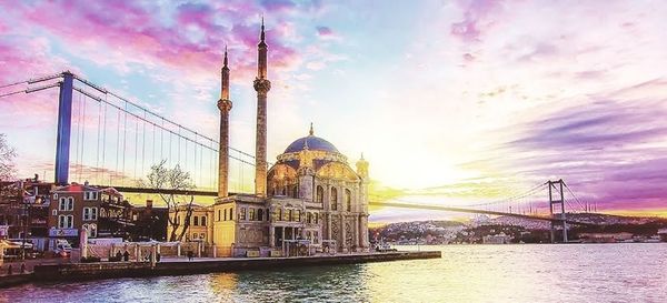 View of mosque at waterfront against cloudy sky