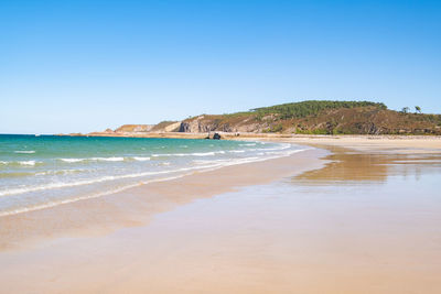 Scenic view of beach against clear blue sky