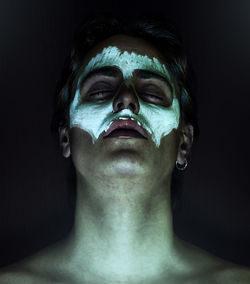 Close-up of man with face paint in darkroom