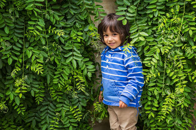 Little child hiding surraunded green leaves