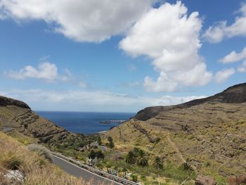 Scenic view of road by sea against sky